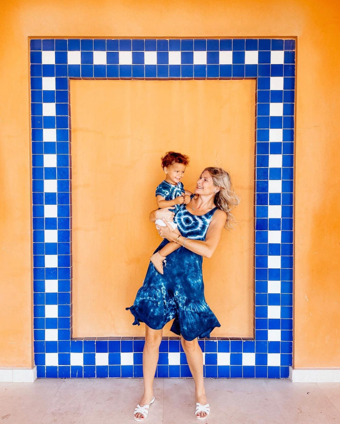 Mom and baby dressed up in bright, colorful outfits for a special occasion, featuring soft toddler shoes designed for all-day comfort