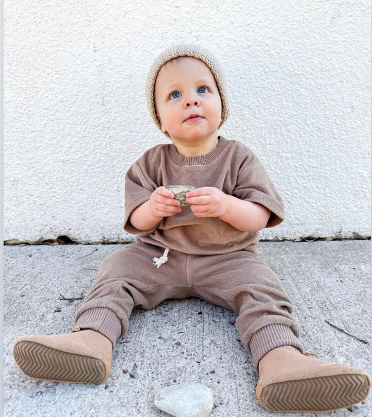 toddler boy with barefoot boots and brown hat and neutral matching set