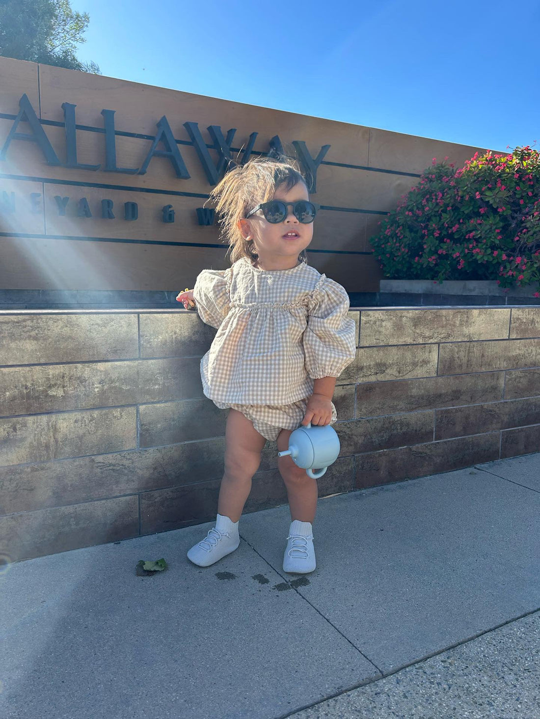 Baby wearing sunglasses and tan Park Boss toddler boots, enjoying a sunny day outdoors in stylish barefoot shoes for early walkers