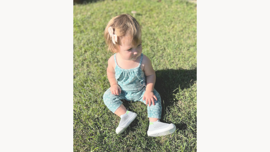 Toddler in the grass happily wearing in barefoot shoes for first walkers, offering flexibility and comfort as they discover the world.