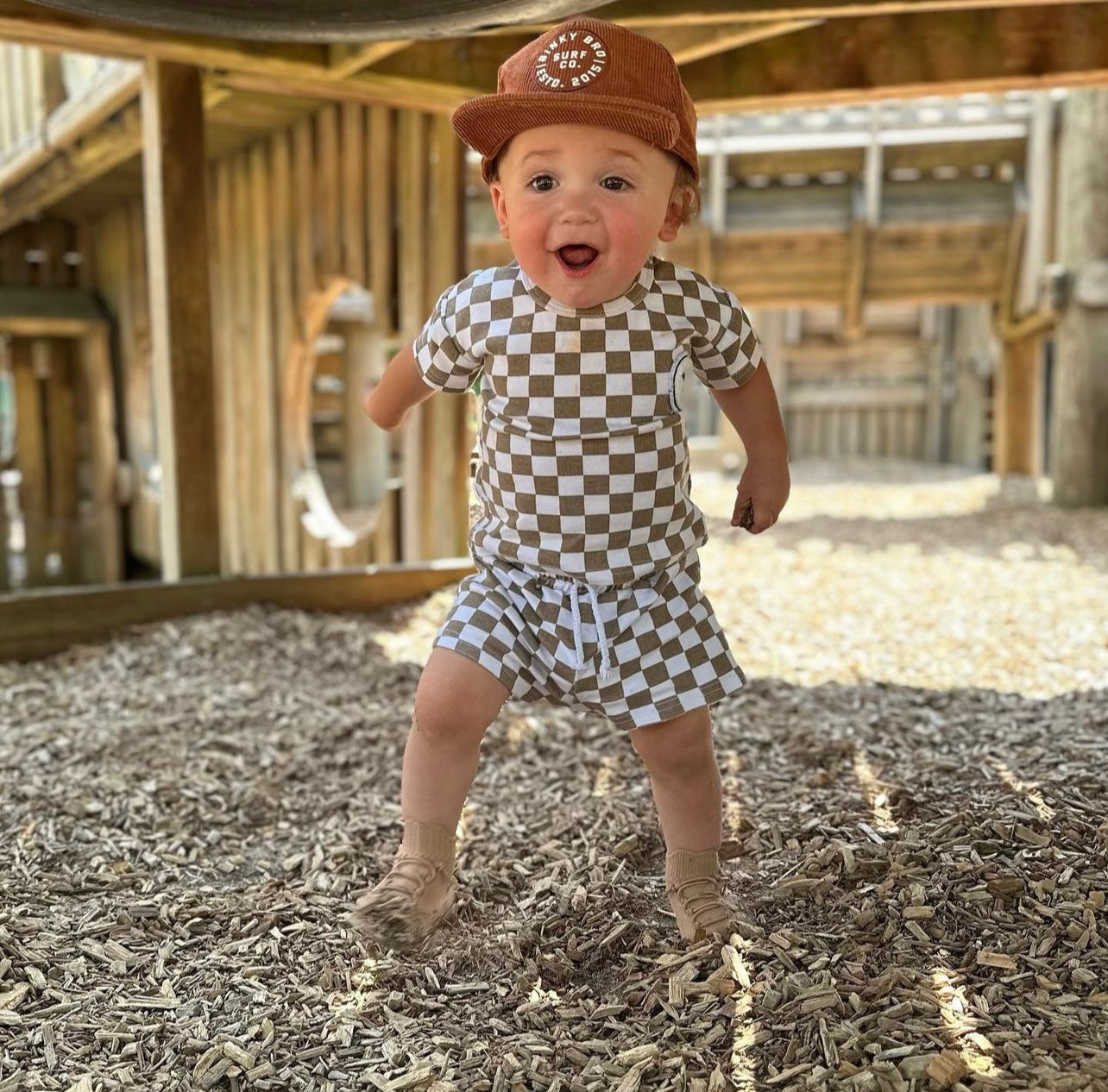 Toddler jumping with baseball cap in first shoes
